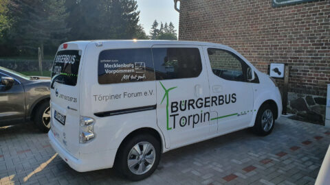 Weißer Kleinbus mit der Aufschrift "Bürgerbus Törpin" auf einem Parkplatz.